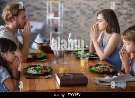 Family praying before meal at home Stock Photo