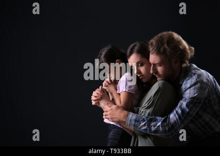 Praying family on dark background Stock Photo