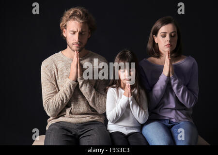 Praying family on dark background Stock Photo