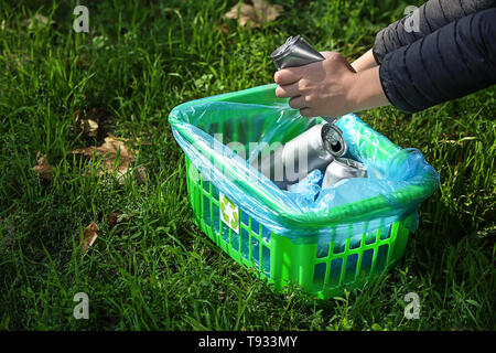Woman gathering empty tin cans in park Stock Photo