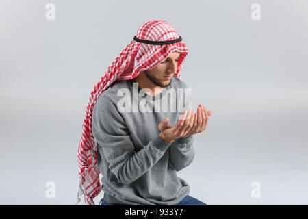 Young Muslim man praying on light background Stock Photo