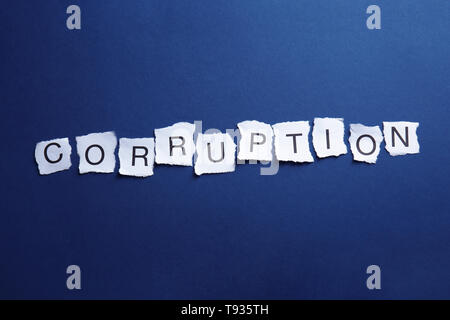 Torn pieces of paper with word CORRUPTION on blue background Stock Photo