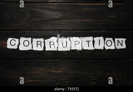 Torn pieces of paper with word CORRUPTION on wooden background Stock Photo