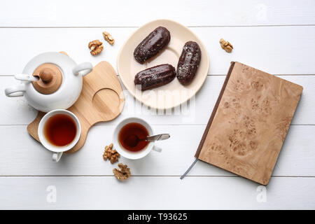 Flat lay composition with delicious eclairs and tea on table Stock Photo