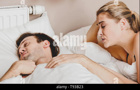 Copule in bed. Woman trying to wake him, in morning. They are waking up. Stock Photo