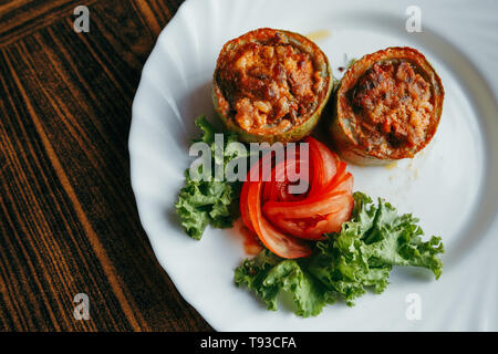 Round zucchini stuffed with vegetables and rice on white plate Stock Photo