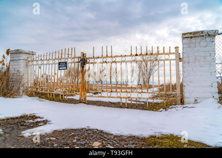 Private property with a No Trespassing sign on the rusty gate viewed in winter Stock Photo
