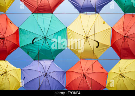Background of multicolored umbrellas hanging against the blue sky. Stock Photo
