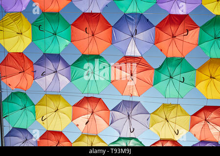 Background of multicolored umbrellas hanging against the blue sky. Stock Photo