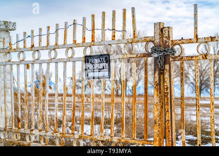 Private Property No Trespassing sign on a rusty gate with chain and padlock Stock Photo