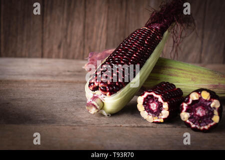 Siam Ruby Queen is super sweet corn with red color, can be eaten fresh place overlap and place on the wood table background Stock Photo