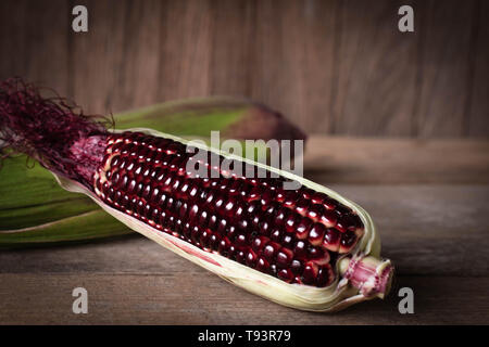 Siam Ruby Queen is super sweet corn with red color, can be eaten fresh place overlap and place on the wood table background Stock Photo
