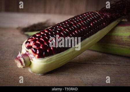 Siam Ruby Queen is super sweet corn with red color, can be eaten fresh place overlap and place on the wood table background Stock Photo