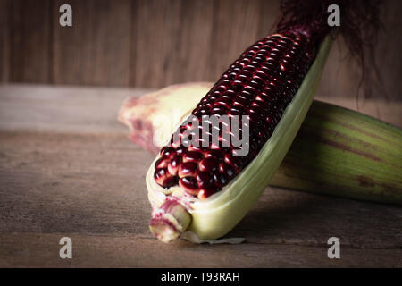 Siam Ruby Queen is super sweet corn with red color, can be eaten fresh place overlap and place on the wood table background Stock Photo