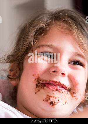 Cute messy with chocolate caucasian girl smiling Stock Photo