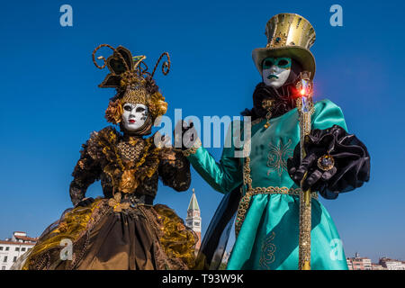 A masked couple in beautiful creative costumes, posing at Grand Canal, Canal Grande, celebrating the Venetian Carnival Stock Photo