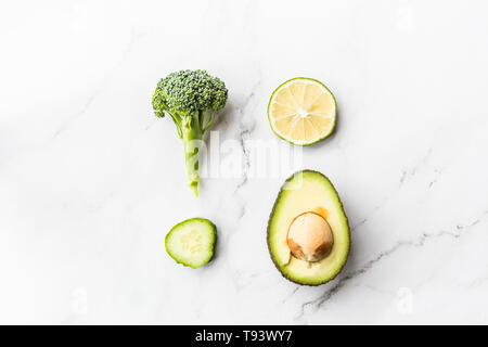 Fresh avocado, lime, broccoli, green peas, cucumber, green pepper. Flat lay. Food concept. Green vegetables lying on white marble background. Stock Photo