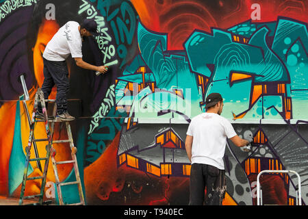 Two graffiti artists making drawings on the wall of a disused site before its demolition Stock Photo