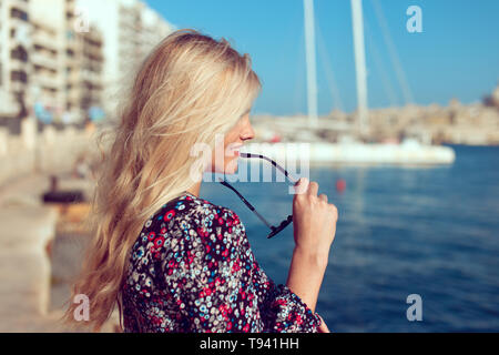 Happy young blonde traveler woman at sea profie view