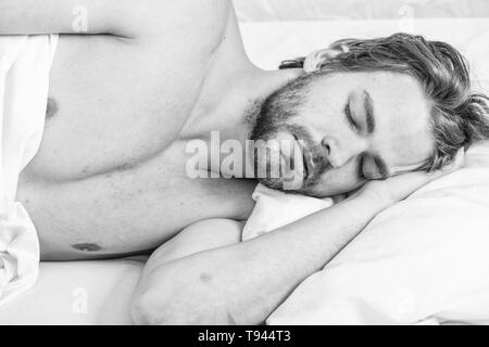 Man handsome guy lay in bed in morning. Tips on how to wake up feeling fresh and energetic. Morning routine tips to feel good all day. How to get up in morning feeling fresh. Late morning overslept. Stock Photo
