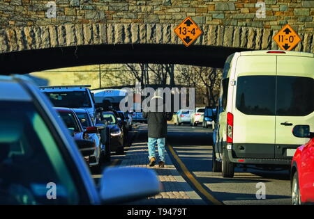 Homeless man walking in between cars asking for donations Stock Photo