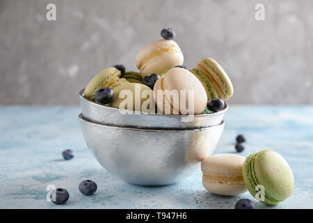 Bowl with sweet macaroons and blueberry on table Stock Photo