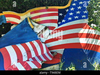 Broken flag, demolished background cardboard with American flag 'Stars and Stripes' as motive, disposed at the roadside. Stock Photo