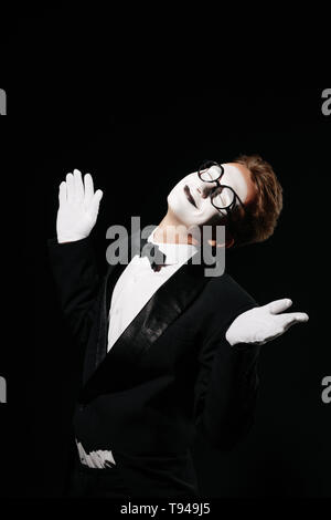portrait of smiling mime man in tuxedo and glasses on black background Stock Photo