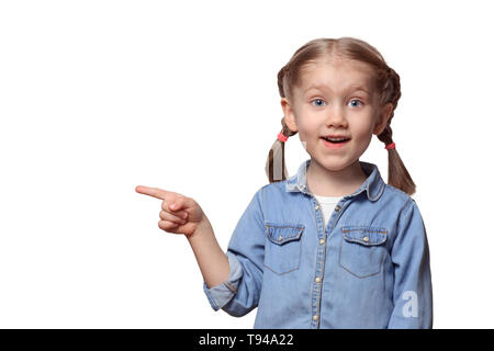 The child is pointing at something. Beautiful girl with pigtails joyfully points a finger upwards. Teenager dressed in a denim shirt. Stock Photo