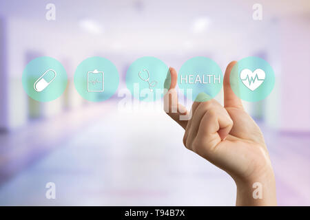 Female doctor presenting health text on transparent display with fingers as futuristic concept Stock Photo
