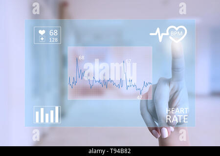 Medic woman touching cardiogram on transparent screen with index finger as modern healthcare concept Stock Photo