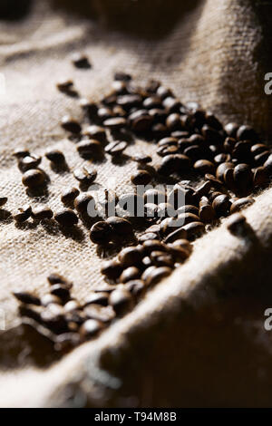 Selective focus of roasted coffee grains on sackcloth texture Stock Photo