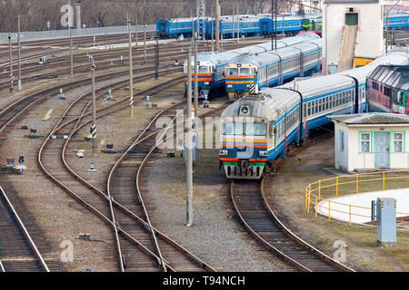 Diesel locomotives and carriages stand in depot with lots of rail forks and rails near railway turntable. Stock Photo