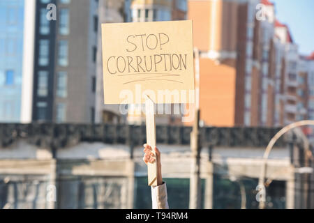 Woman holding placard with text STOP CORRUPTION outdoors Stock Photo