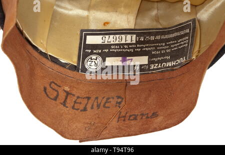 A visor cap for enlisted men/NCOs of the Allgemeine-SS regulation issue Black cloth, black trim band, white piping, beige silk liner, beneath the cap trapezoid large gold-stamped runes and size designation '56', beneath the brown leather sweatband an SS/RZM tag, the inside of the sweatband with handwritten wearer's identification 'Steiner Hans', the underside of the visor with the ink stamping 'RZM SS', silvered non-ferrous metal insignia, black patent leather straps. A lightly used visor cap. historic, historical, 20th century, Editorial-Use-Only Stock Photo