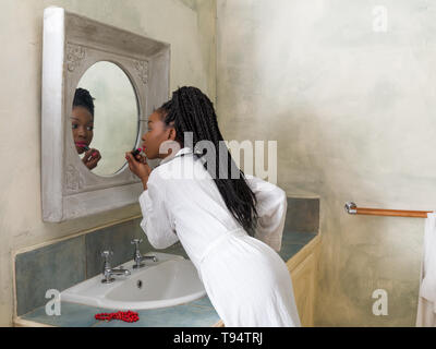 Pretty young african american woman doing her morning routine in front of the bathroom mirror Stock Photo