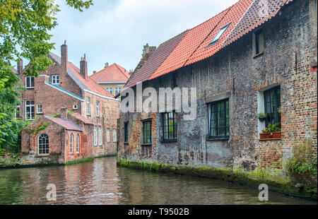 Bruges, Belgium. Medieval ancient houses made of old bricks at water channel with boats in old town. Stock Photo