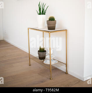 interior decoration; golden-marble side table with indoor plants on the parquet floor Stock Photo