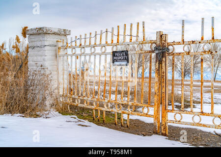 Private Property No Trespassing sign on a rusty metal gate viewed in winter Stock Photo