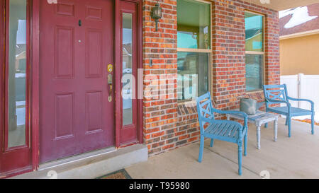 Clear Panorama Facade of a home with a red front door and reflective sidelights and windows Stock Photo