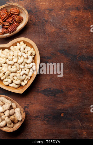 Various nuts selection: cashew, hazelnuts, chestnuts and pecans on wooden table. With space for your text Stock Photo