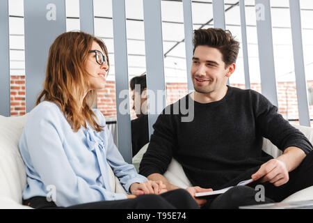 Cheerful young couple of colleagues working together at the office, co-working teamwork concept Stock Photo