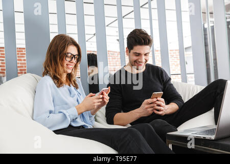 Cheerful young couple of colleagues working together at the office, co-working teamwork concept Stock Photo