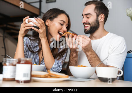 Happy multiethnic couple having breakfast at the kitchen Stock Photo