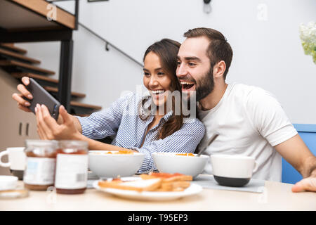 Happy multiethnic couple having breakfast at the kitchen Stock Photo