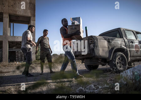 Tripoli, Libya. 16th May, 2019. Fighters from UN-backed government forces distribute food and aid to civilian workers trapped in abandoned farms in the fighting areas near Al-Sawani frontline in Tripoli, Libya, on May 16, 2019. At least six civilians were reported killed and five more injured in an apparent airstrike in populated areas of the Libyan capital of Tripoli, Stephane Dujarric, spokesman for UN Secretary-General Antonio Guterres, said on Thursday. Credit: Amru Salahuddien/Xinhua/Alamy Live News Stock Photo