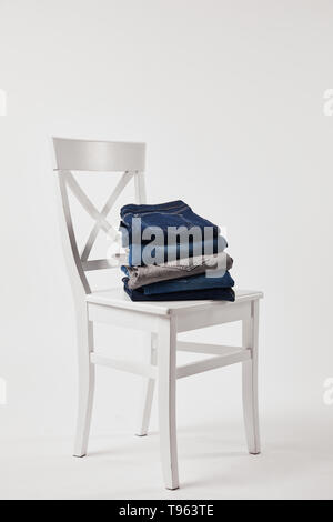 Wooden chair with folded denim pants on white Stock Photo