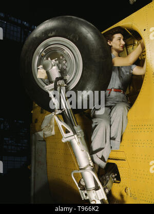 This woman worker at the Vultee-Nashville is shown making final adjustments in the wheel well of an inner wing before the installation of the landing gear, Nashville, Tenn. This is one of the numerous assembly operations in connection with the mass production of Vultee Vengeance dive bombers. Although the image of 'Rosie the Riveter' reflected the industrial work of welders and riveters, the majority of working women filled non-factory positions in every sector of the economy. Stock Photo