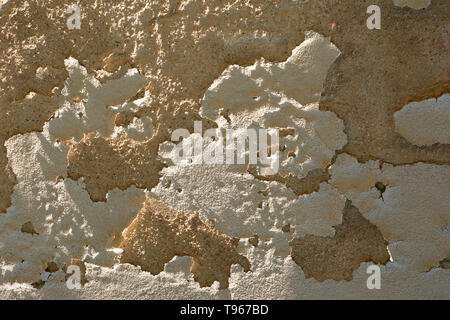 dirty and old cracked damaged plaster wall background lit by the midday sun, rough damaged plaster wall Stock Photo