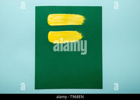 top view of green canvas with yellow brushstrokes isolated on blue Stock Photo